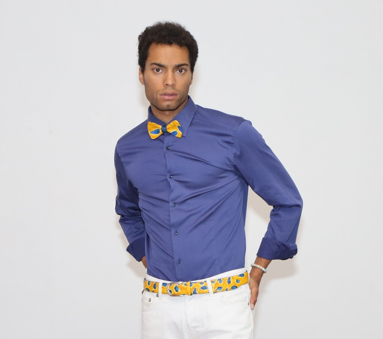 our model wearing white pants and a blue shirt with painted bow tie and belt in a white background