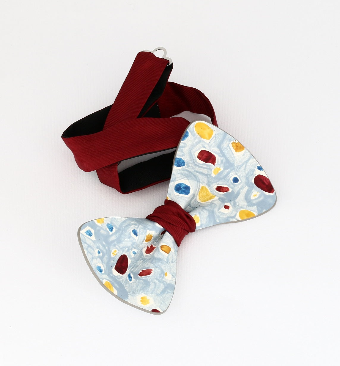 harlequin's choice hand painted bow tie with blue yellow and red dots on a light blue background